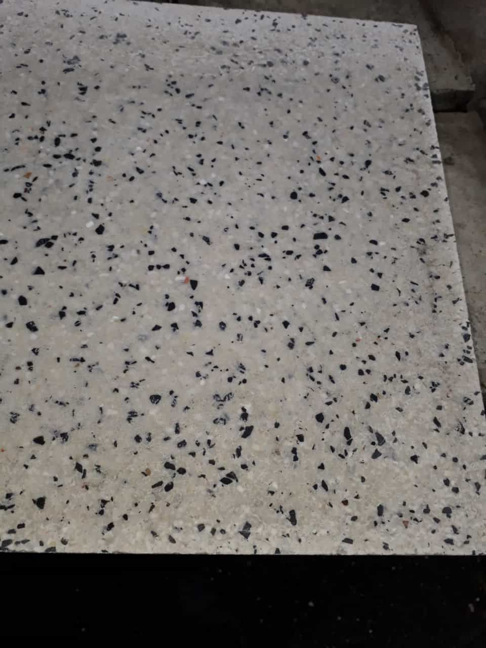 Beyaz zemin üzerine yerleştirilmiş siyah ve gri doğal taş parçacıklarından oluşan 30x30x3 cm ebatında terrazzo karo