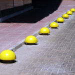 Şehir peyzajı için gri renkte, silindirik formda beton park mantarı, yeşil bir alanda güvenlik ve estetik sağlamak üzere kullanılıyor.