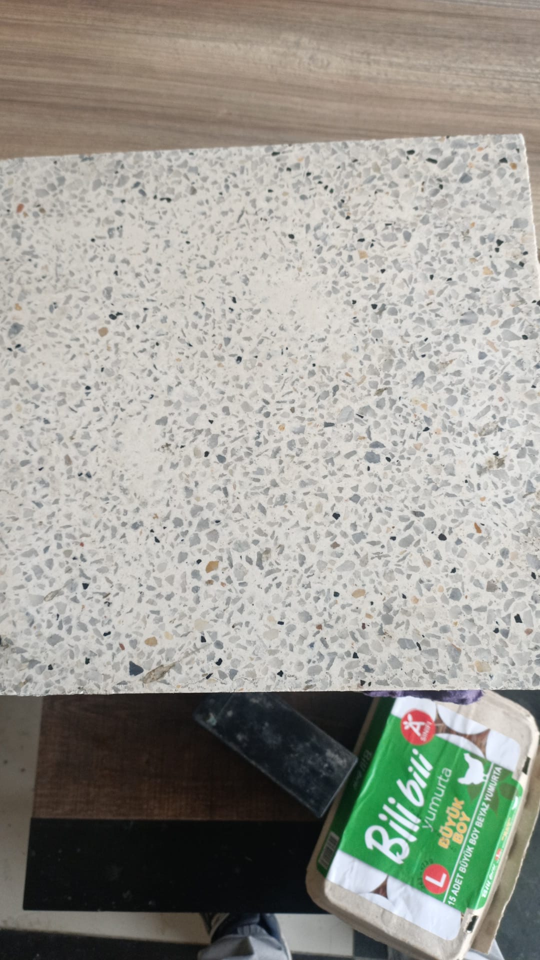 Beyaz ve gri tonlarda doğal taş parçacıkları içeren, cilalı yüzeyli 30x30 cm boyutunda Terrazzo Karo örneği.